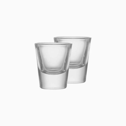 Two clear glass shot glasses on a white background