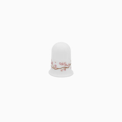 A set of white dinnerware with a pink floral pattern, including plates, bowls, and mugs.