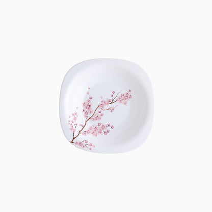 A set of white dinnerware with a pink floral pattern, including plates, bowls, and mugs.
